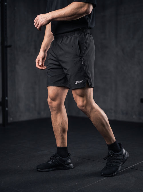 XZIZT gym shorts in black, model doing lateral shuffle #Color_Black