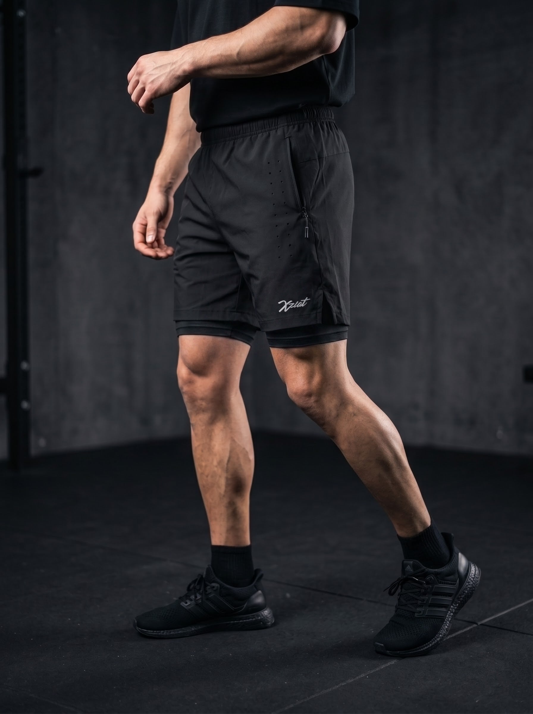 XZIZT gym shorts in black, model doing lateral shuffle #Color_Black